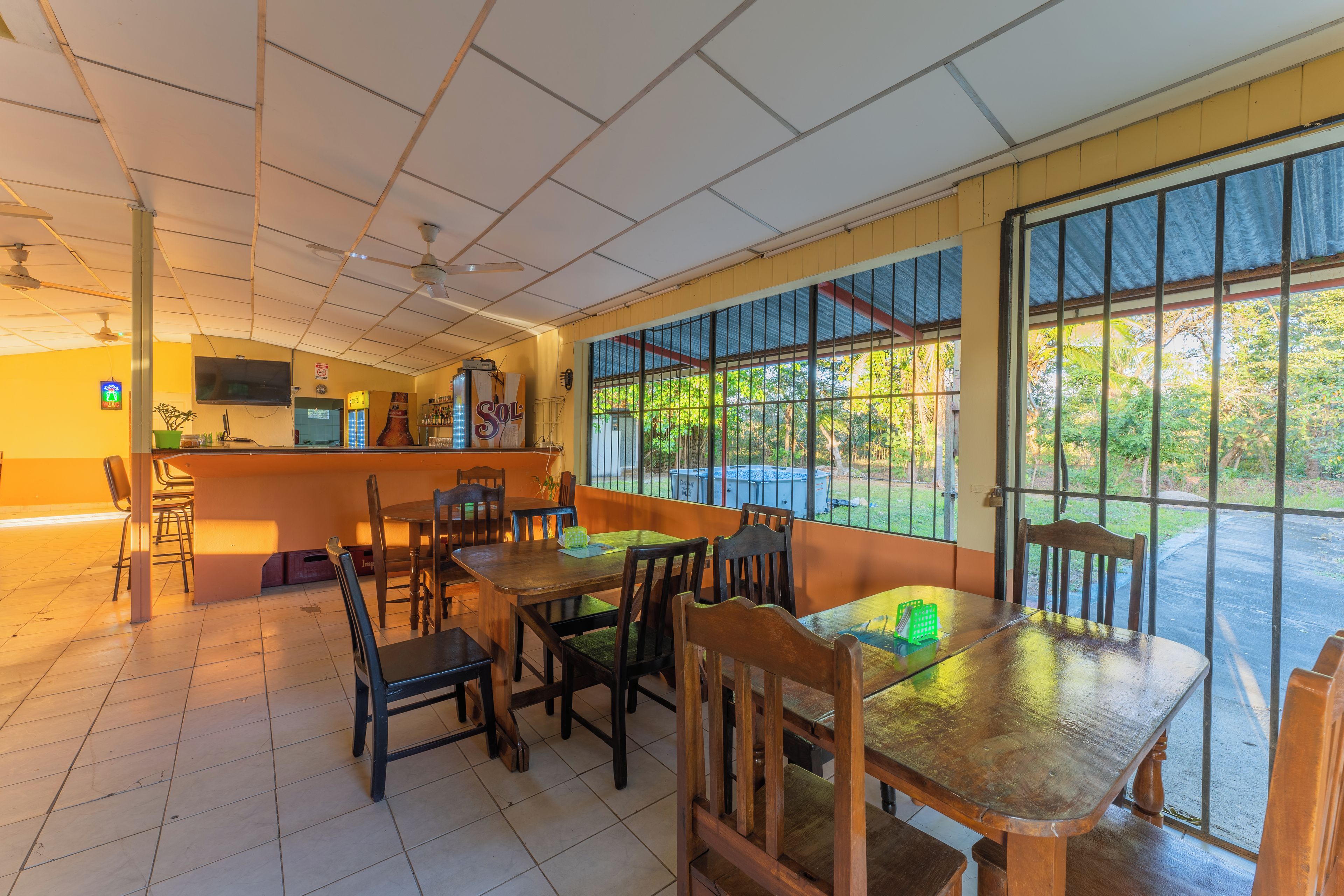 A restaurant with a bar area, multiple tables and chairs, and large windows offering a view of the outdoors.