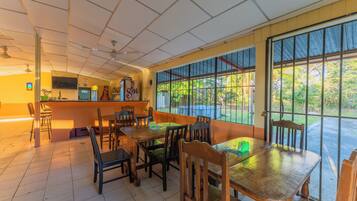 A restaurant with a bar area, multiple tables and chairs, and large windows offering a view of the outdoors.