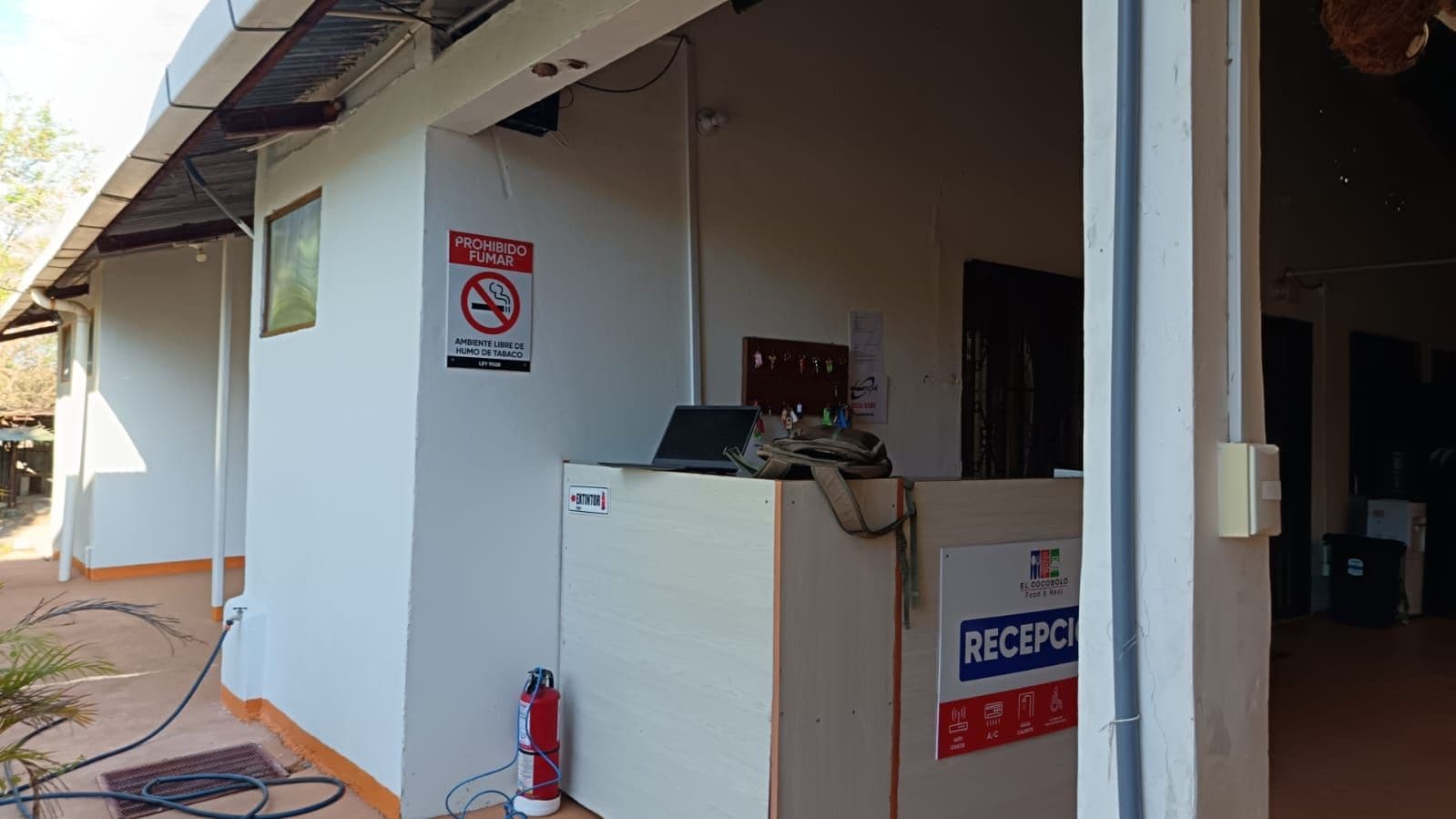 A reception area with a sign indicating it is a no-smoking zone and a sign for 'RECEPCION' which suggests a reception desk.