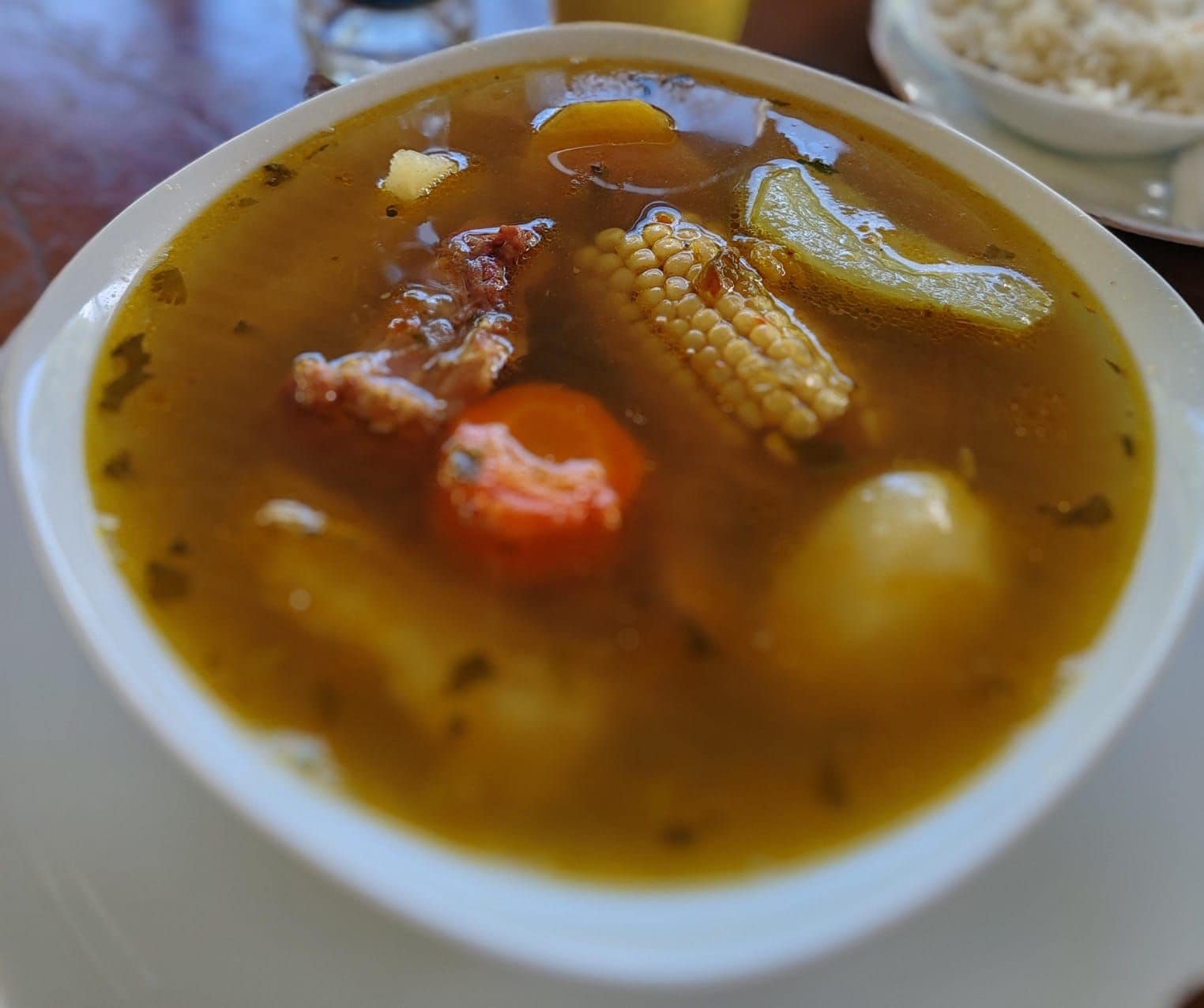 Eine Schüssel Suppe mit sichtbaren Zutaten wie Mais, Karotten und Kartoffeln.