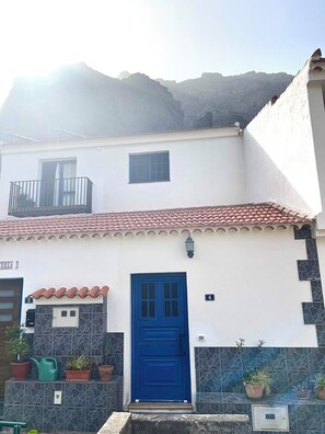A building with a blue door, a balcony, and a mountain backdrop. - An oasis of peace in the heart of Valle Gran Rey (Valle Gra Rey)