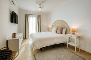 A bedroom with a bed, bedside tables, a TV, a ceiling fan, and a window with curtains. - Villa in Lanzarote | Pool | Private Garden (Yaiza)