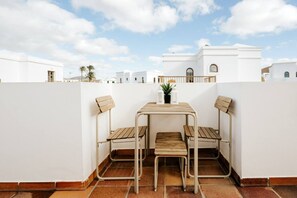 A rooftop terrace with a table and chairs, a potted plant, and a white wall. - Villa in Lanzarote | Pool | Private Garden (Yaiza)