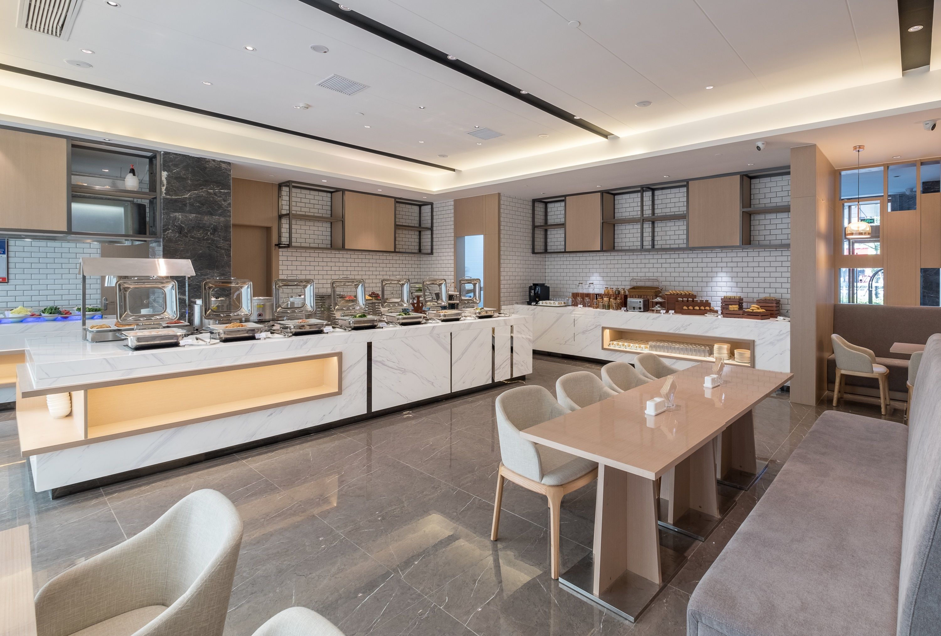 Una cucina moderna con piani in marmo, un'isola centrale e un'area pranzo con un tavolo lungo e sedie.