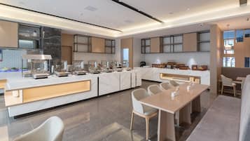 Una cucina moderna con piani in marmo, un'isola centrale e un'area pranzo con un tavolo lungo e sedie.