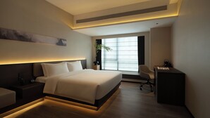 Habitación de hotel moderna con una cama grande, un escritorio y una ventana con persianas.