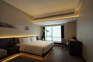 Una camera d'hotel moderna con un letto grande, una scrivania e una finestra con persiane.