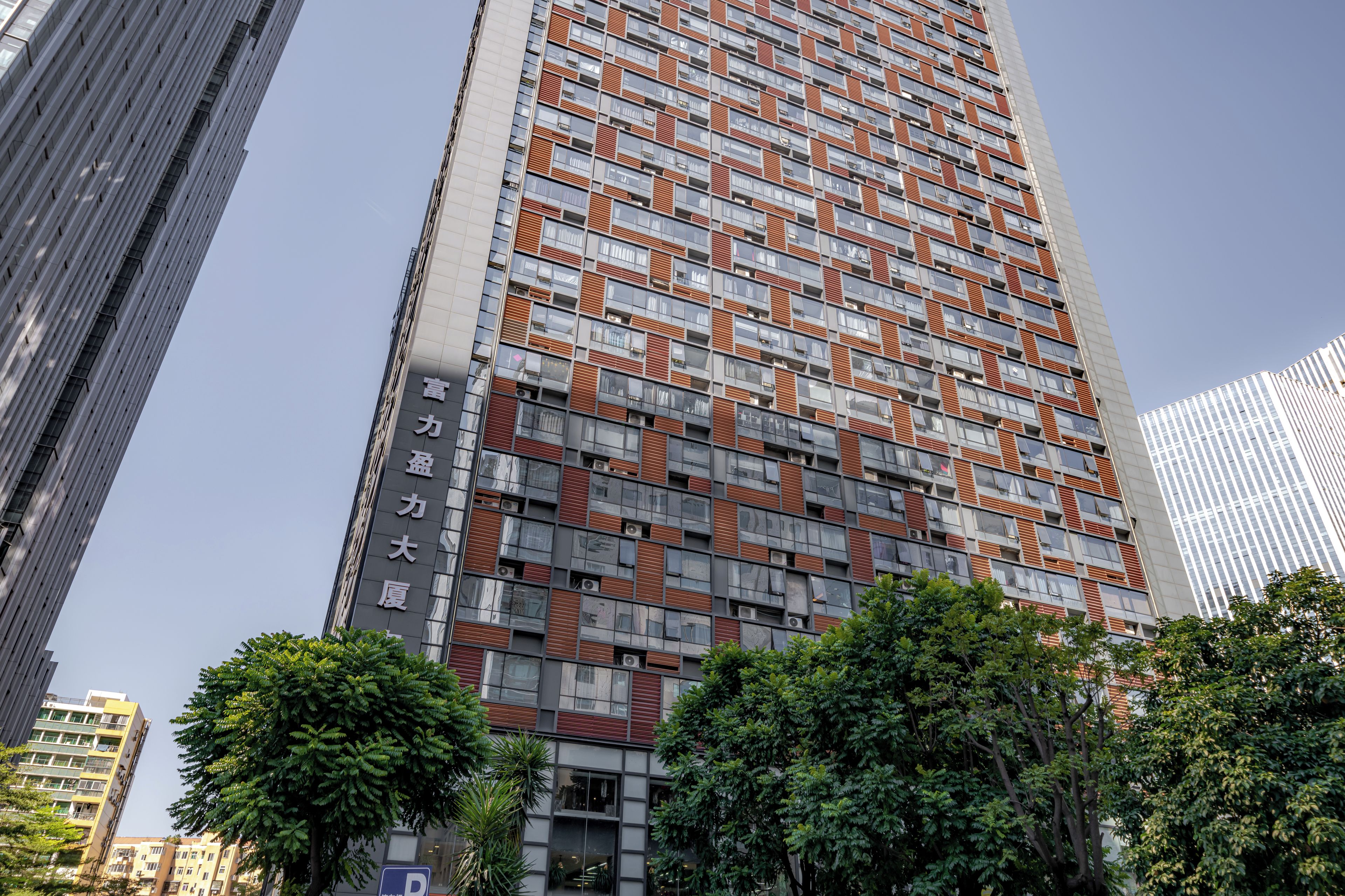 Un edificio de gran altura con fachada decorada, rodeado de árboles y otros edificios.