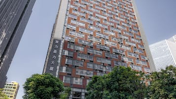 Un edificio de gran altura con fachada decorada, rodeado de árboles y otros edificios.