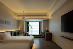 Una camera d'albergo con un letto, una scrivania, una sedia, una TV e una pianta.