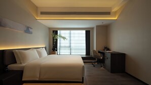Habitación de hotel moderna con cama, escritorio y vistas a la ciudad.