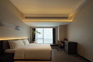 Una moderna camera d'albergo con un letto, una scrivania e vista sulla città.