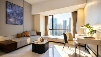 Una habitación de hotel moderna con un ventanal grande, un sofá, un escritorio y una silla.