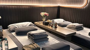 Une salle de spa moderne équipée de deux tables de massage, chacune ayant un coussin et une bouteille d’eau.