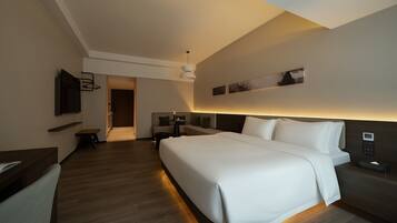 Una habitación de hotel moderna con una cama grande, mesitas de noche, un televisor y un escritorio.