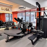 Un gimnasio con equipamiento de levantamiento de pesas, una banca y un aire acondicionado de pared.