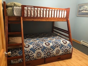 A bunk bed with a patterned bedspread, wooden frame, and a ladder. - "Inn The Pines" 2-bedroom apartment in charming Jay, NY (Jay)