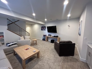 Ein Wohnzimmer mit einer Couch, einem Couchtisch, einem Fernseher und einer Treppe.