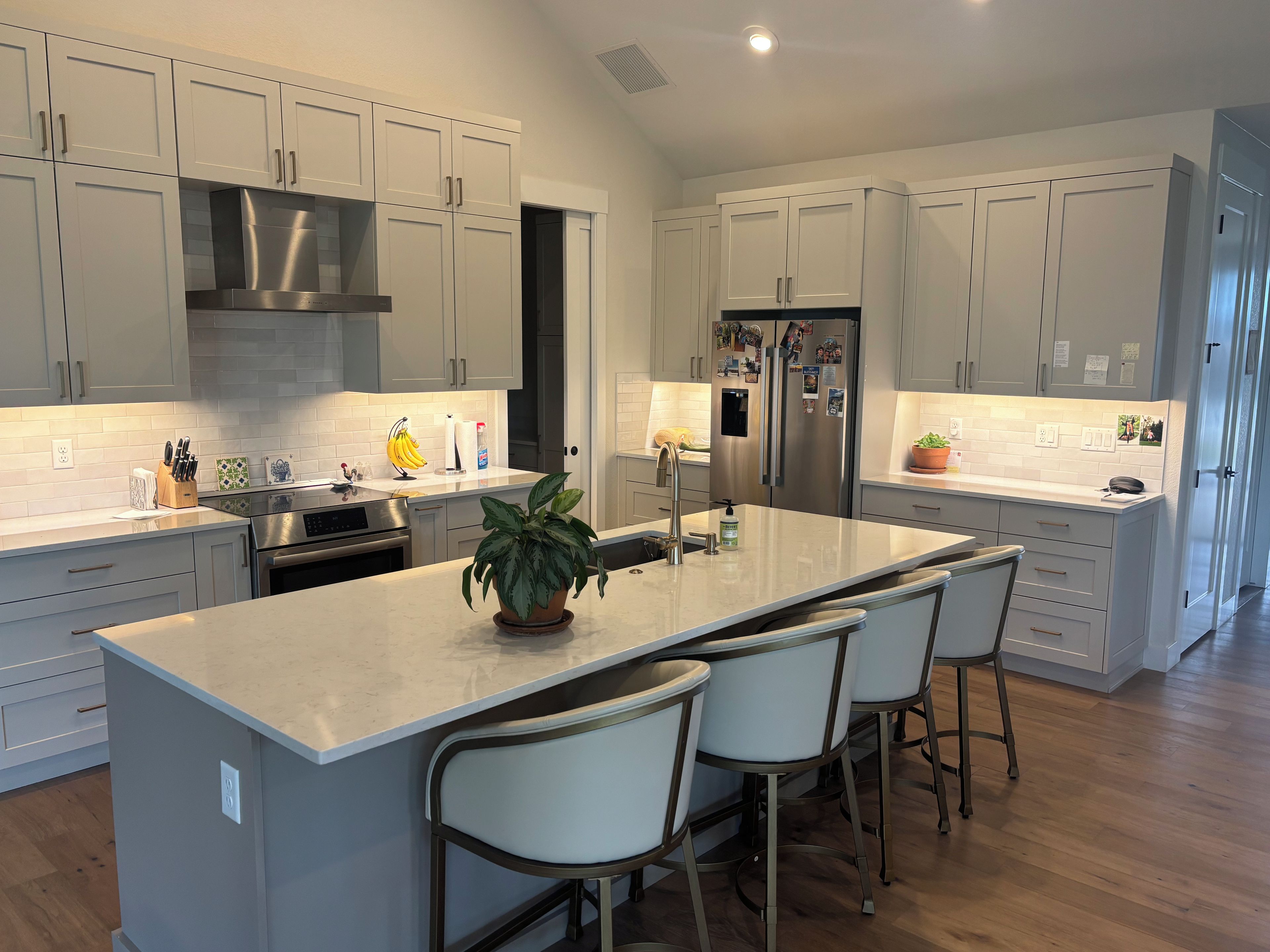 A modern kitchen with white cabinets, stainless steel appliances, and a central island with bar stools.