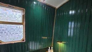 Un baño con tocador de madera, un lavabo blanco, un espejo y una pequeña ventana con diseño de mosaico.