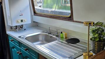 A compact kitchen with a built-in water heater, a sink, and a window overlooking a street.