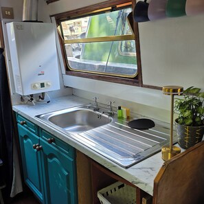 A compact kitchen with a built-in water heater, a sink, and a window overlooking a street.