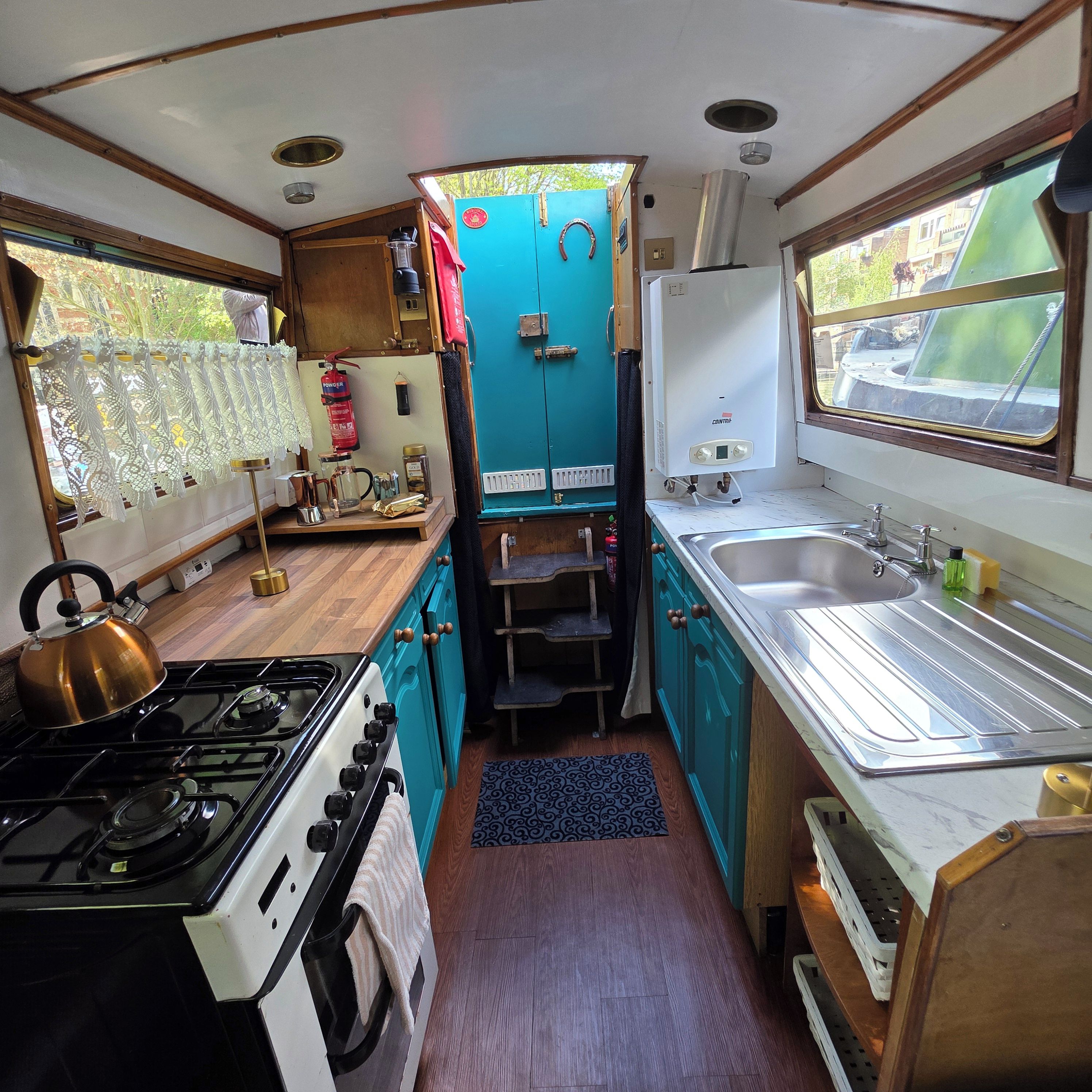 Una cocina compacta con estufa a gas, un lavamanos y una ventana.
