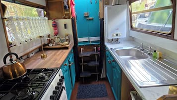 Una cocina compacta con estufa a gas, un lavamanos y una ventana.