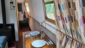 Un comedor con una mesa preparada para dos, una ventana con cortinas y una kitchenette al fondo.