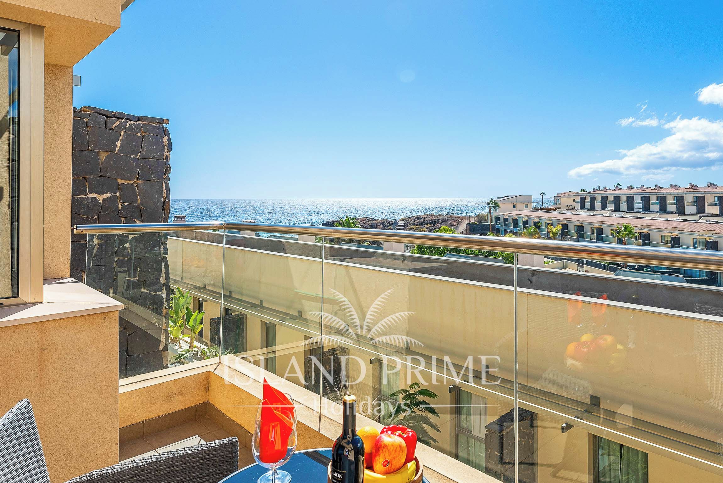 A balcony with a clear view of the sea and a cityscape.