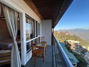 Ein Balkon mit Blick auf eine gebirgige Landschaft, einem Sofa und zwei Holzstühlen.