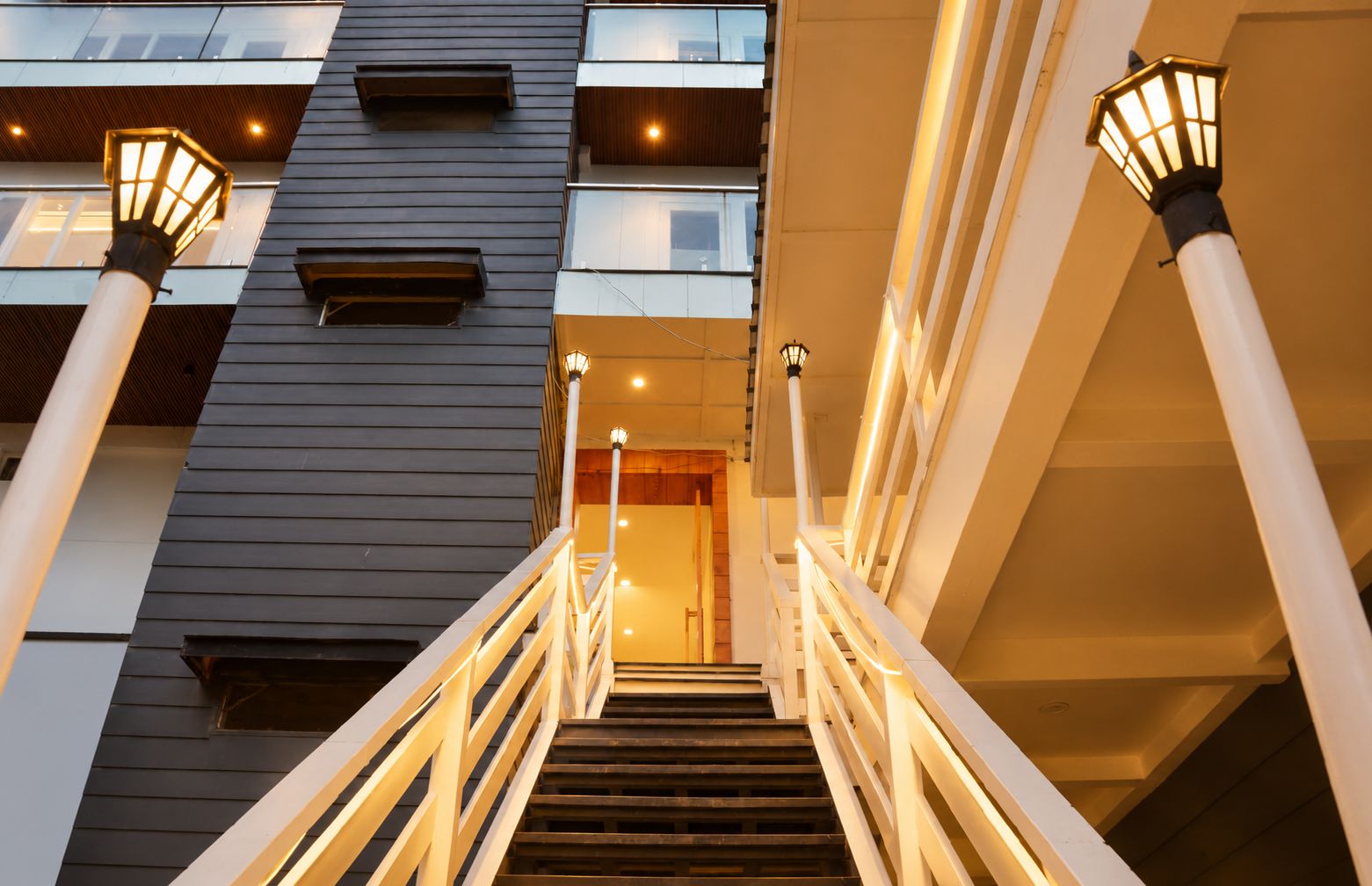 A staircase leading to an interior space with a modern design, featuring a railing and wall-mounted lights.