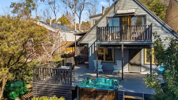 Una casa de dos pisos con un balcón, un jacuzzi y una terraza.