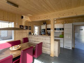 A wooden interior with a dining area, kitchen, and a large window. - Cabin With 1 Bedroom (Sankt Georgen am Kreischberg)