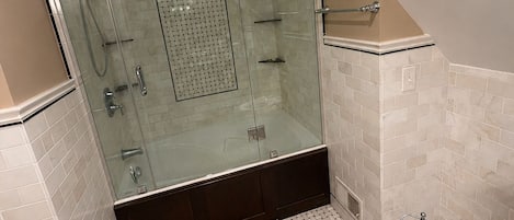 A modern bathroom with a glass-enclosed shower, a bathtub, and a toilet.
