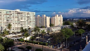 Un edificio residencial de varios pisos con balcones, una zona de estacionamiento y palmeras.
