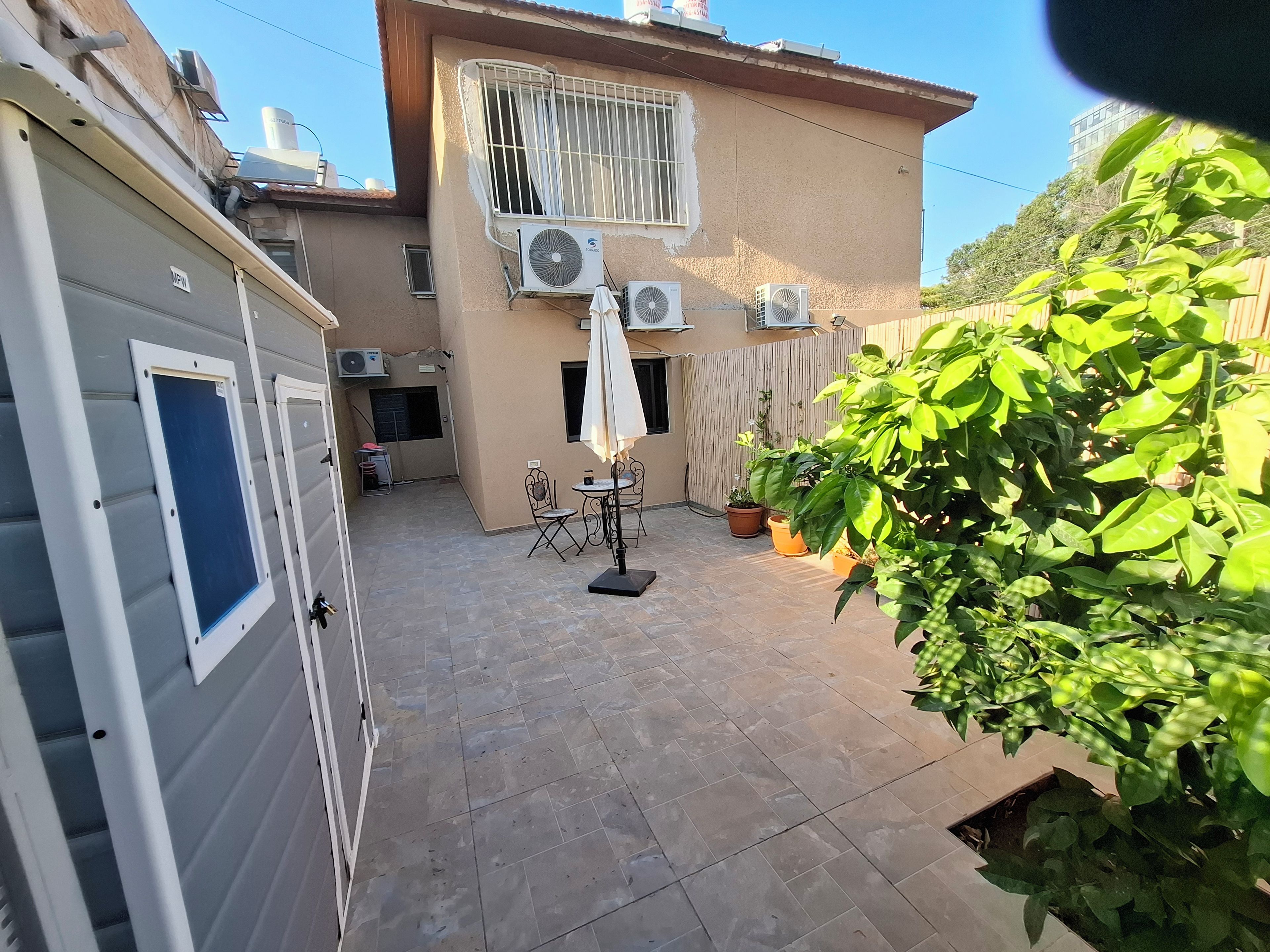 A courtyard with a tiled floor, a table with chairs, and potted plants.