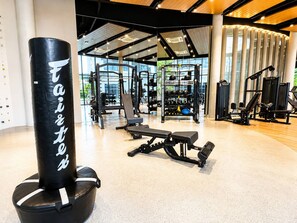 A gym with various exercise equipment, including a punching bag, benches, and weight machines. - 1Br Condo for Long Stay in Ekkamairamindra (Bangkok)