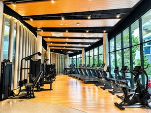 Ein Fitnessstudio mit Cardiogeräten, Krafttrainingsgeräten und großen Fenstern mit Blick ins Freie.