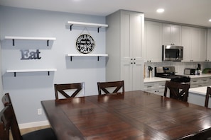 Una cocina moderna con armarios blancos, una mesa de comedor con sillas y un letrero en la pared que dice 'Coffee & Friends Make the Perfect Blend'.