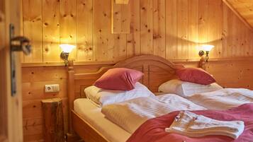 A wooden cabin room with two beds, each with a headboard and bedside lamps.