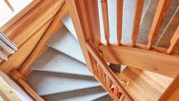 A wooden staircase with a carpeted landing and a view of a white fence outside.