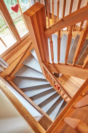 A wooden staircase with a carpeted landing and a view of a white fence outside.