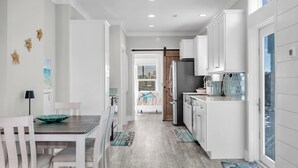A modern kitchen with white cabinetry, a stainless steel refrigerator, and a dining area with a wooden table and chairs. - Tropic Paradise. New 2 bedroom 2 bath ocean front home in Islamorada (Islamorada)