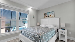 A bedroom with a bed, a nightstand, a wall-mounted painting, and a window with blinds. - Tropic Paradise. New 2 bedroom 2 bath ocean front home in Islamorada (Islamorada)