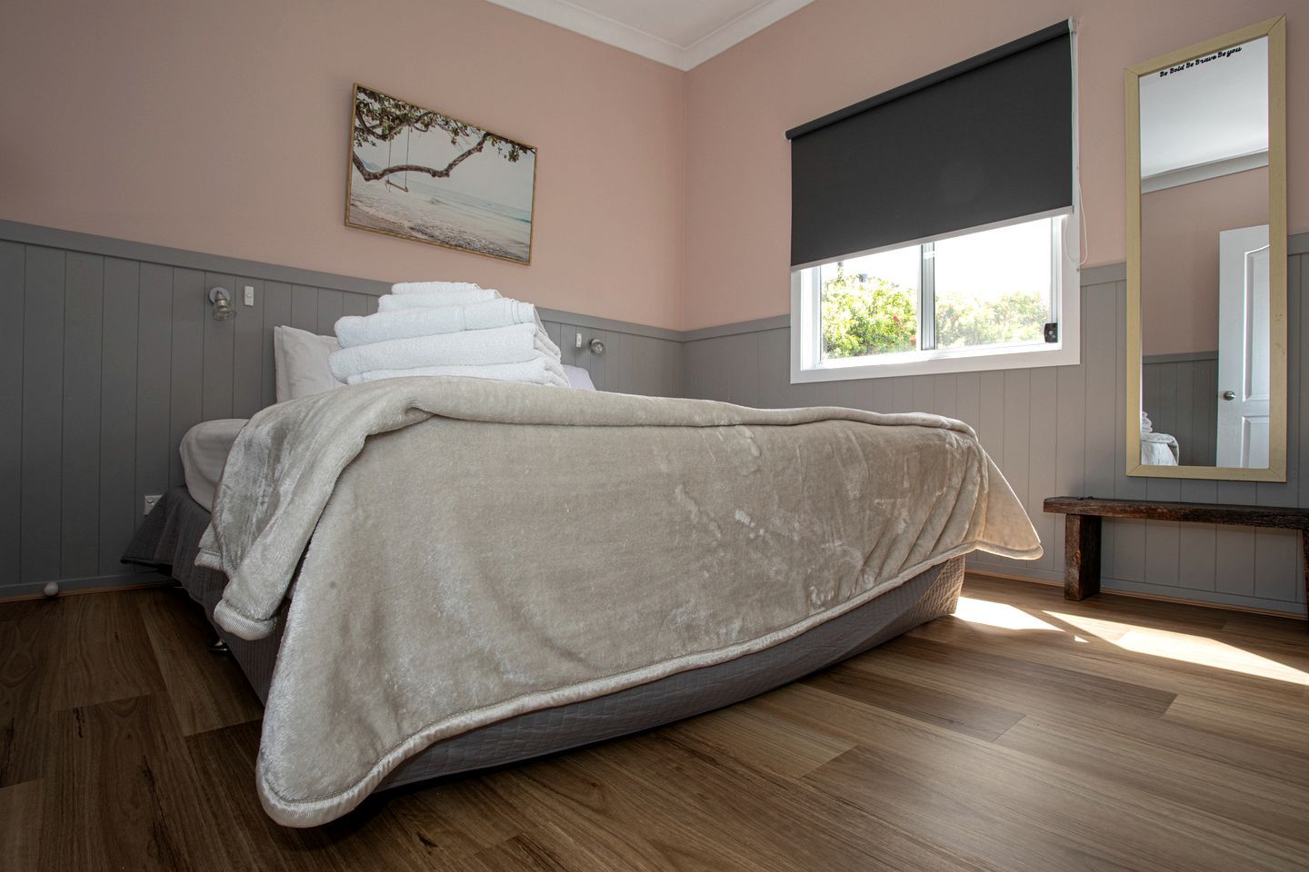 Una camera da letto con un letto, una finestra, una panca e uno specchio.