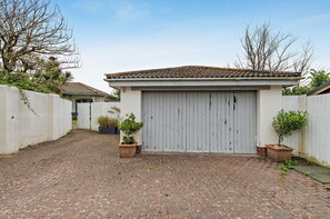 A building with a tiled roof, a white door, and a paved driveway. - Host & Stay - Lindens (Croyde)