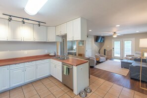 Una cocina moderna con armarios blancos, encimera de madera y horno empotrado.