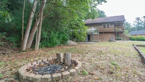 A backyard with a fire pit, a house, and surrounding trees. - EZ Carriage House by Lake Monroe (Bloomington)