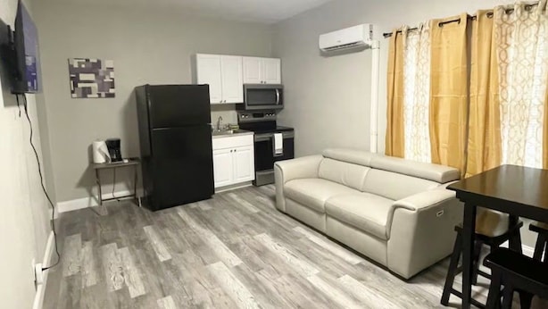 A compact living space with a kitchenette, a sofa, a dining table, and a television mounted on the wall. - 2BR APT close to Ybor, Downtown, Airport, Busch Gardens & Adventure Island (Tampa)